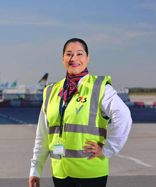 Een vrolijke vrouw die staat op de landingsbaan en werkt in de beveiliging op Eindhoven Airport