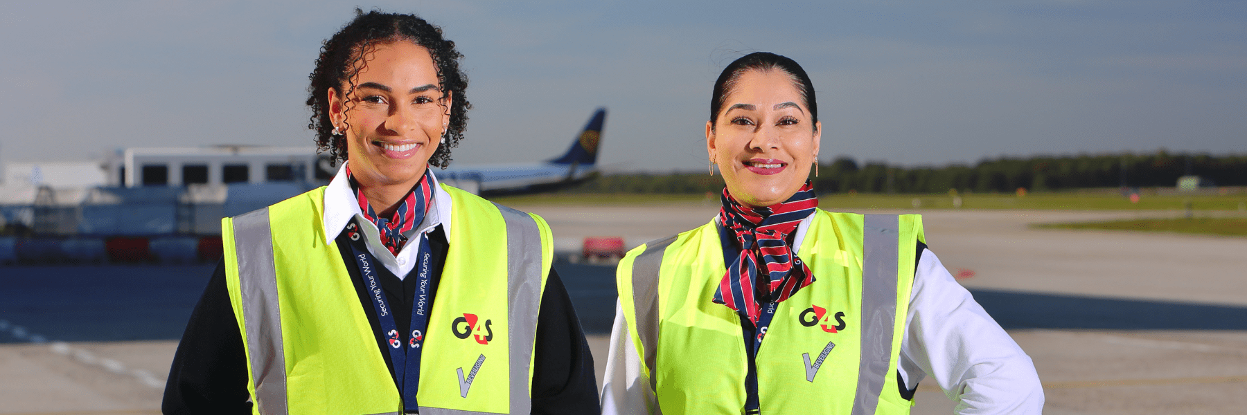 Twee vrolijke vrouwen die staan op de landingsbaan en werken in de beveiliging op Eindhoven Airport