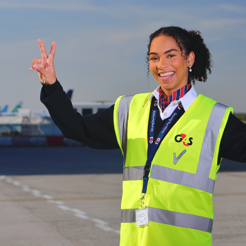 Een vrolijke vrouw die staat op de landingsbaan en werkt in de beveiliging op Eindhoven Airport